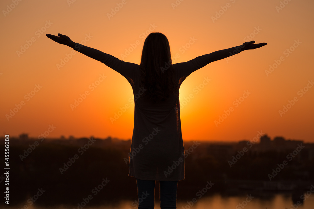 Fototapeta premium Silhouette of a woman meditating at the sunset.