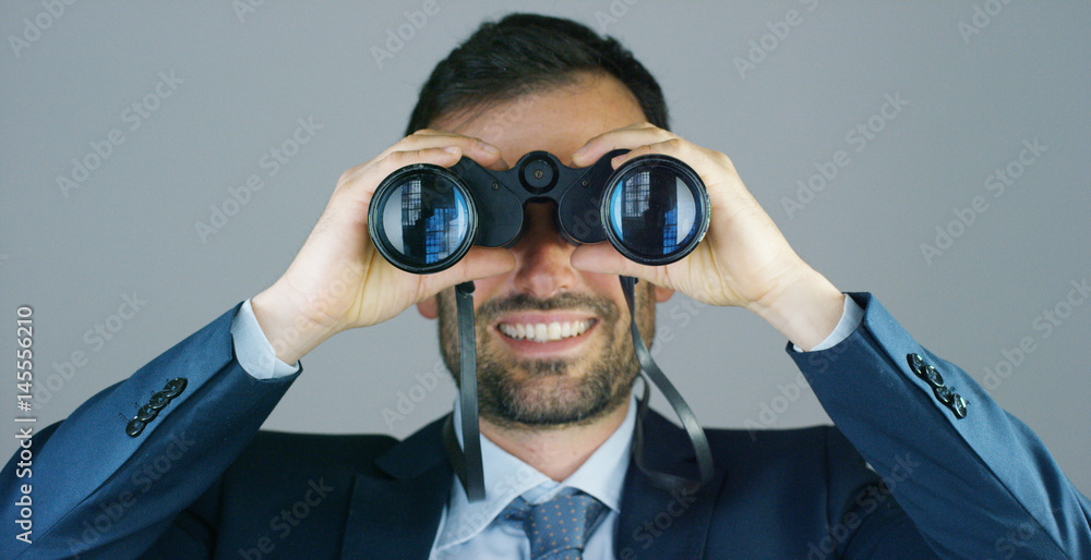 A businessman in a suit and tie, use the binoculars to look away with the concept of looking to the future, forecasting the economic and financial growth and the future