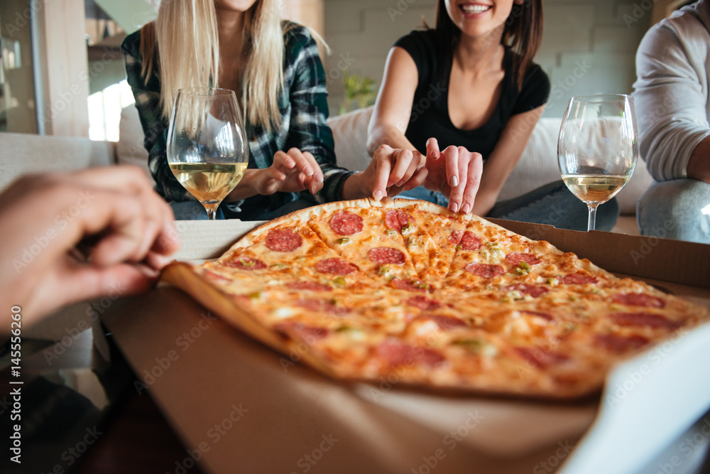 Group of friends eating big pizza and drinking