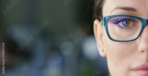 Portrait of a beautiful girl with glasses, with green eyes, shot close-up, on a blurred background. Concept: beautiful eyes, beautiful smile, vision, perfect skin.