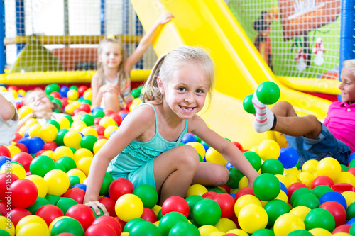 portrait of girl playing in pool with plastic multicolored balls