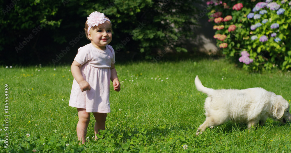 On a sunny spring day a little girl dressed as a ballerina plays with her mom and Golden Retriever puppy in the garden and everyone smiles like a happy family On a sunny spring day a little girl dressed as a ballerina plays with her mom and Golden Retriever puppy in the garden and everyone smiles like a happy family
