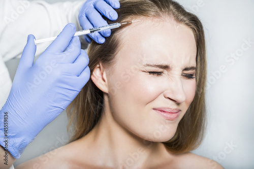 Doctor aesthetician makes head beauty injections to female patient