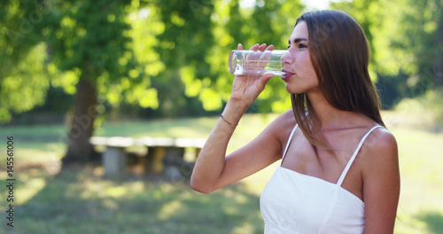 young woman drinks at sunset in a green world a cup of cold water and pure. concept of sustainability, nature and purity of fresh water and purified