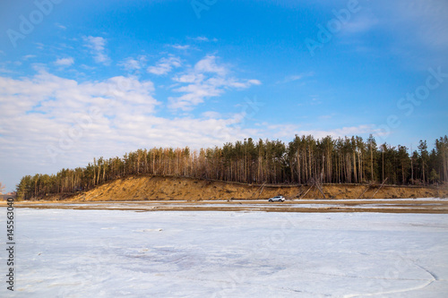 Wallpaper Mural White car is standing in the spring on a sandy beach on a background of a cliff and forest and blue sky Torontodigital.ca