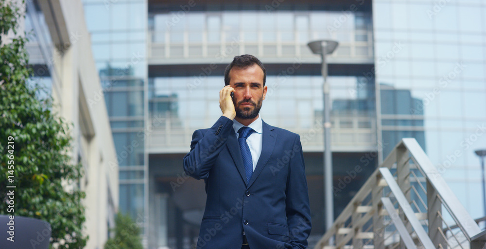 Fototapeta premium On escalators, a businessman answers the phone, send messages and smiles for the beautiful job news. Concept: technology, telephony, business trips, business. 