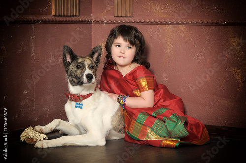 Little girl in red Indian sari and dog photo