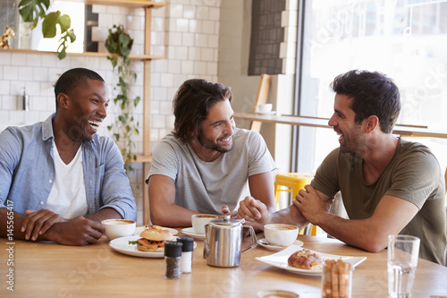 Three Male Friends Meeting For Lunch In Coffee Shop photo