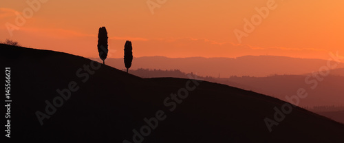 Typical Tuscany hills panoramic landscape on counterlight sunset, Orcia Valley, Siena, Italy photo