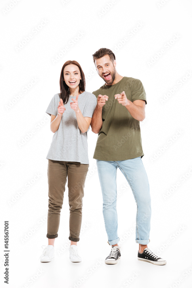 Happy young loving couple standing isolated and pointing. Happy young loving couple standing isolated and pointing.