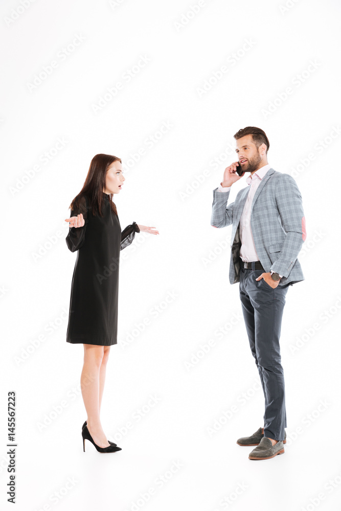 Angry woman looking at man talking by phone Angry woman looking at man talking by phone