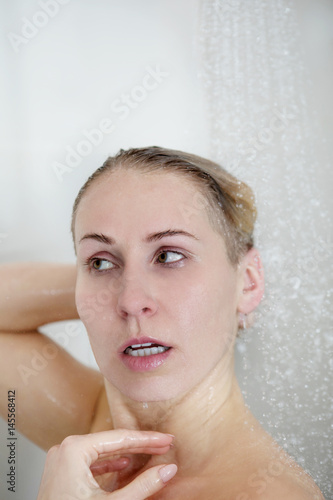 Beautiful naked woman washing her hair while taking shower.