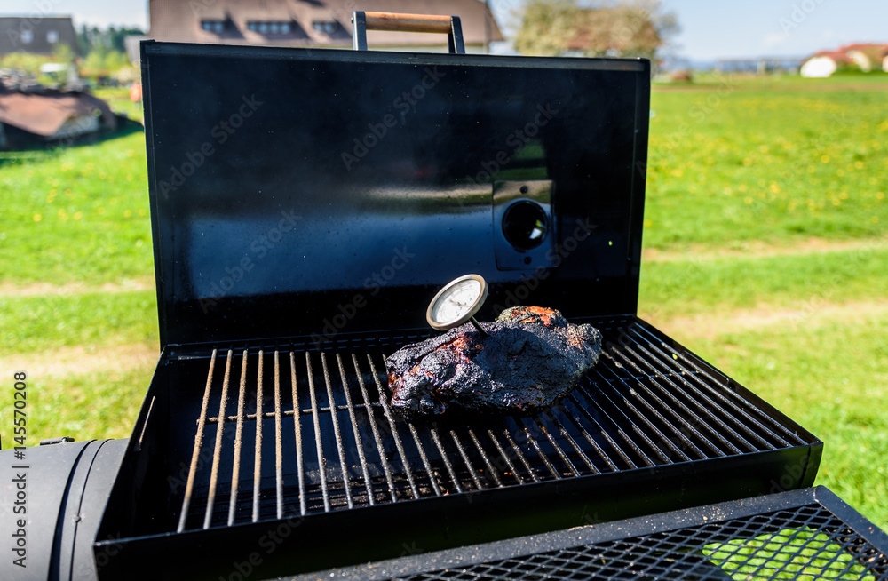 Preparing delicious meat in slow cooking smoker in backyard. Preparing delicious meat in slow cooking smoker in backyard.
