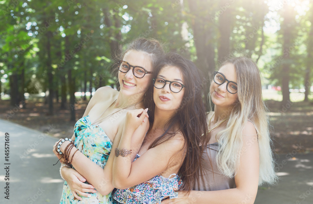 Naklejka premium Three beautiful young boho chic stylish girls walking in park.