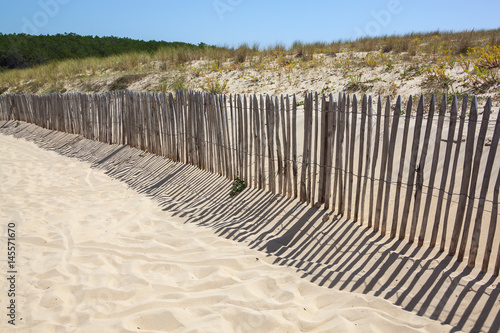Wooden fence and his shadows on the sand on an Atlantic coastline in France