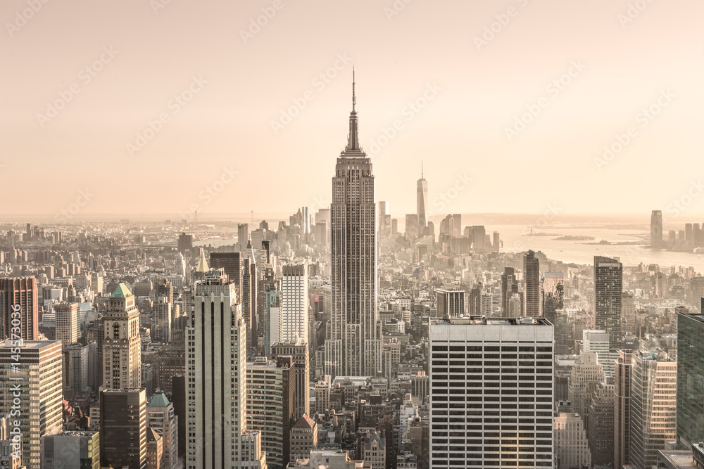 Obraz premium New York City. Manhattan downtown skyline with sun illuminated Empire State Building and skyscrapers at sunset.