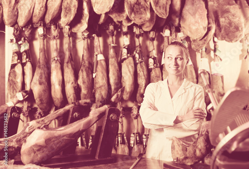 Fototapeta Naklejka Na Ścianę i Meble -  Woman seller working with iberian jamon in grocery