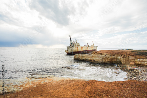 Abandoned broken ship-wreck beached on rocky sea shore.