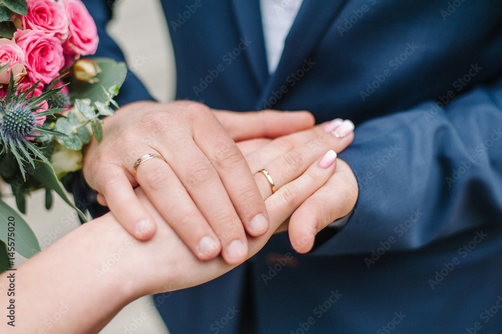 Hands of newlyweds with wedding rings.