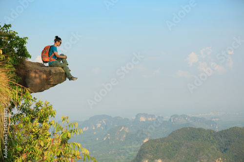 successful woman hiker enjoy the view on mountain peak cliff