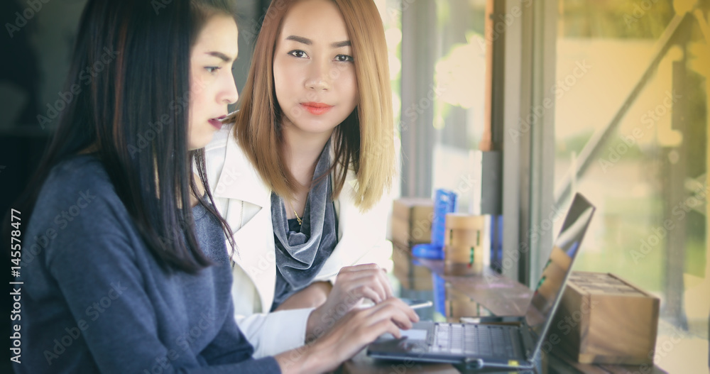 Two Asian business women using notebook working and Discussion of the important contract at office Two Asian business women using notebook working and Discussion of the important contract at office