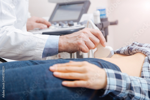 Skillful doctor using professional equipment in the sonography cabinet