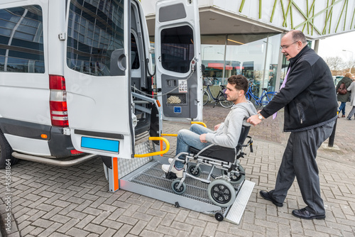 Taxi Driver Assisting Man On Wheelchair To Board Van © corepics
