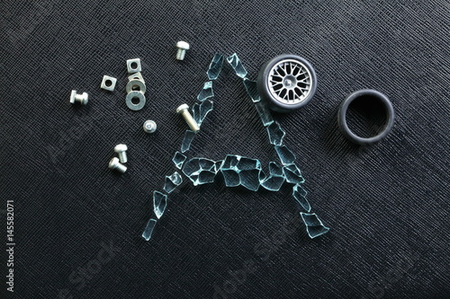 Plastic model of aluminum alloy wheel among broken tempered glass represent the damaged abstract meaning.