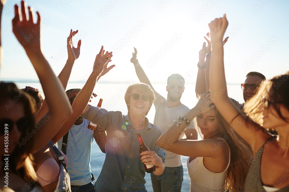 Ecstatic buddies dancing with raised hands at beach party Ecstatic buddies dancing with raised hands at beach party