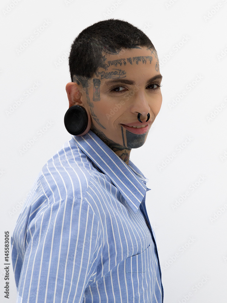 Pessoa com rosto tatuado e alargador