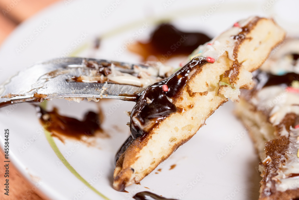 Slice of american pancake topped with chocolate cream and sprinkles on the fork closeup macro Slice of american pancake topped with chocolate cream and sprinkles on the fork closeup macro
