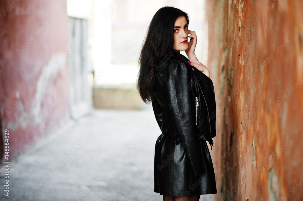 Young goth girl on black leather skirt and jacket against grunge wall. Young goth girl on black leather skirt and jacket against grunge wall.