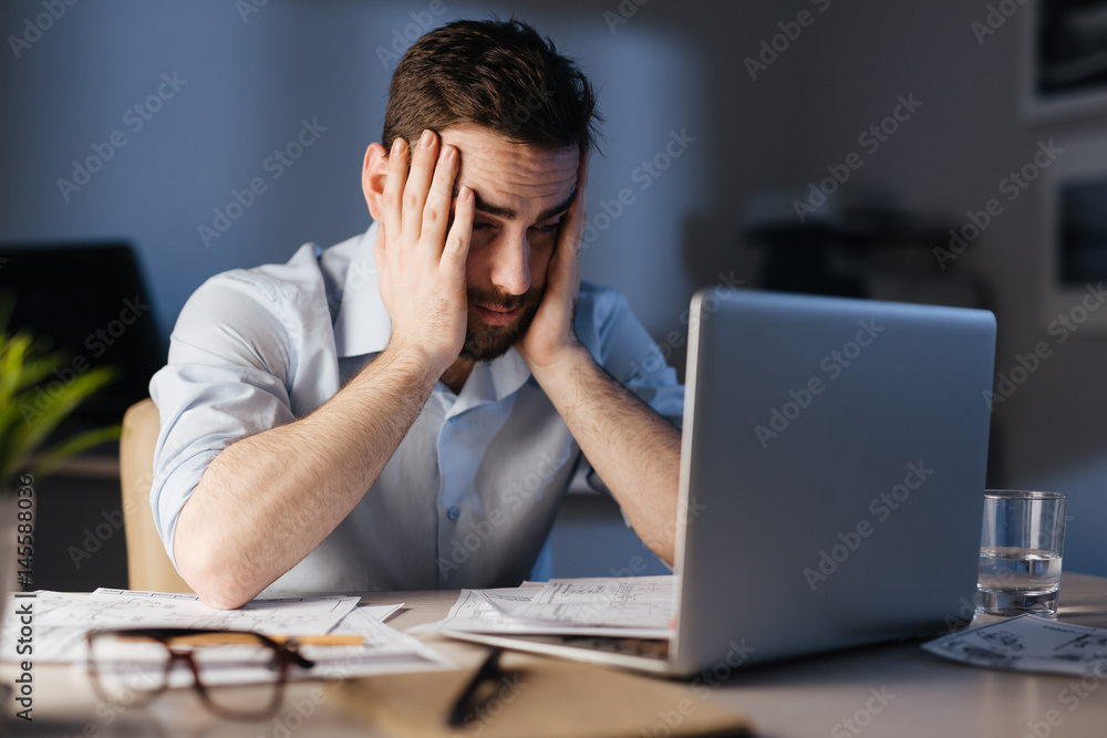 Overworked businessman sitting in front of laptop Overworked businessman sitting in front of laptop