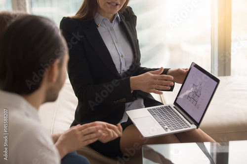 Fotografie Female real estate agent offering young married couple of buyers house for sale,