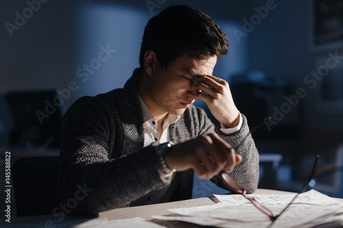 Stressed businessman sitting in office in late evening