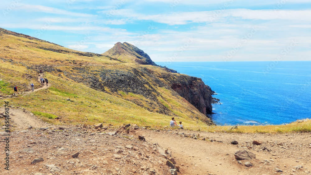 trekking to Sao Lourenco. Amazing cliff view panorama with tourists sitting on the edge. Madeira island, Portugal