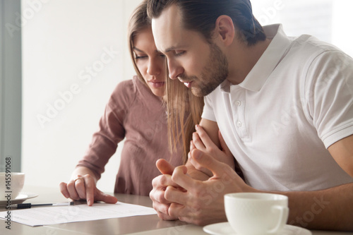 Obraz na plátně Serious couple studying contract agreement, reading terms and conditions attenti