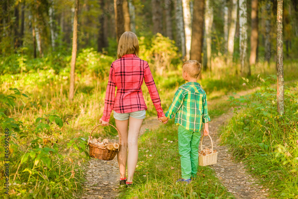 Brother and sisters picking mushrooms in the forest Brother and sisters picking mushrooms in the forest