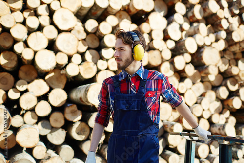 Tree felling worker with headphones pulling cart photo