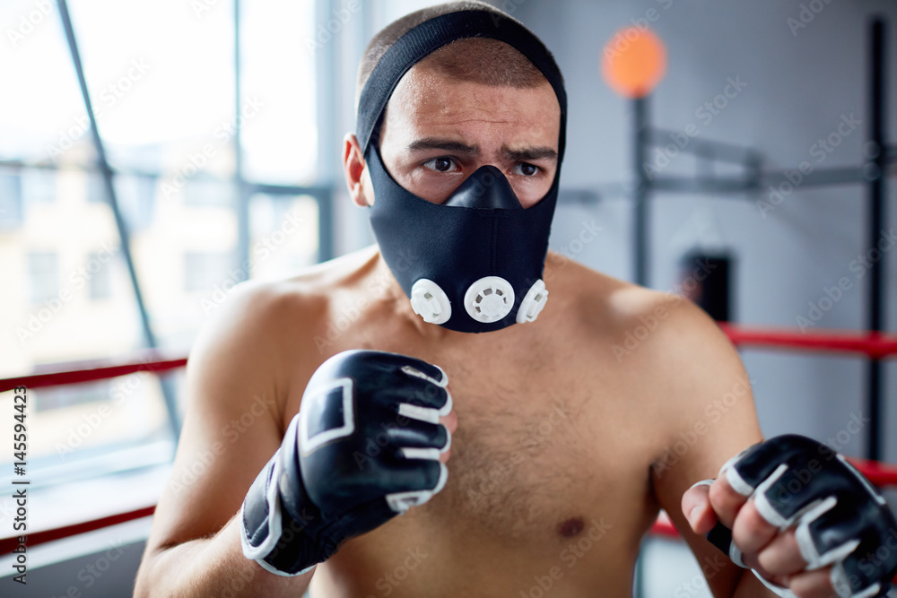 Portrait of shirtless boxer standing in fighting pose in boxing ring