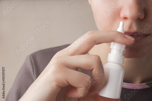 Foto A woman with a runny nose holds a medicine in her hand, a red nose