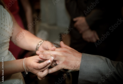 Close up hands of bride and groom putting on a wedding rings
