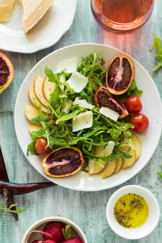 Fresh spring salad with arugula, pear and orange slices and walnuts on wooden table. Selective focus