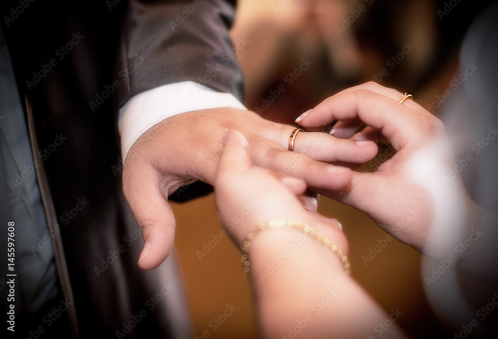 Fototapeta premium Close up hands of bride and groom putting on a wedding rings
