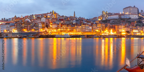 Panorama of Ribeira and Old town of Porto with mirror reflections in the Douro River during evening blue hour, Portugal, Portugal.