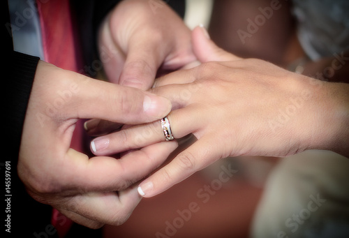 Close up hands of bride and groom putting on a wedding rings
