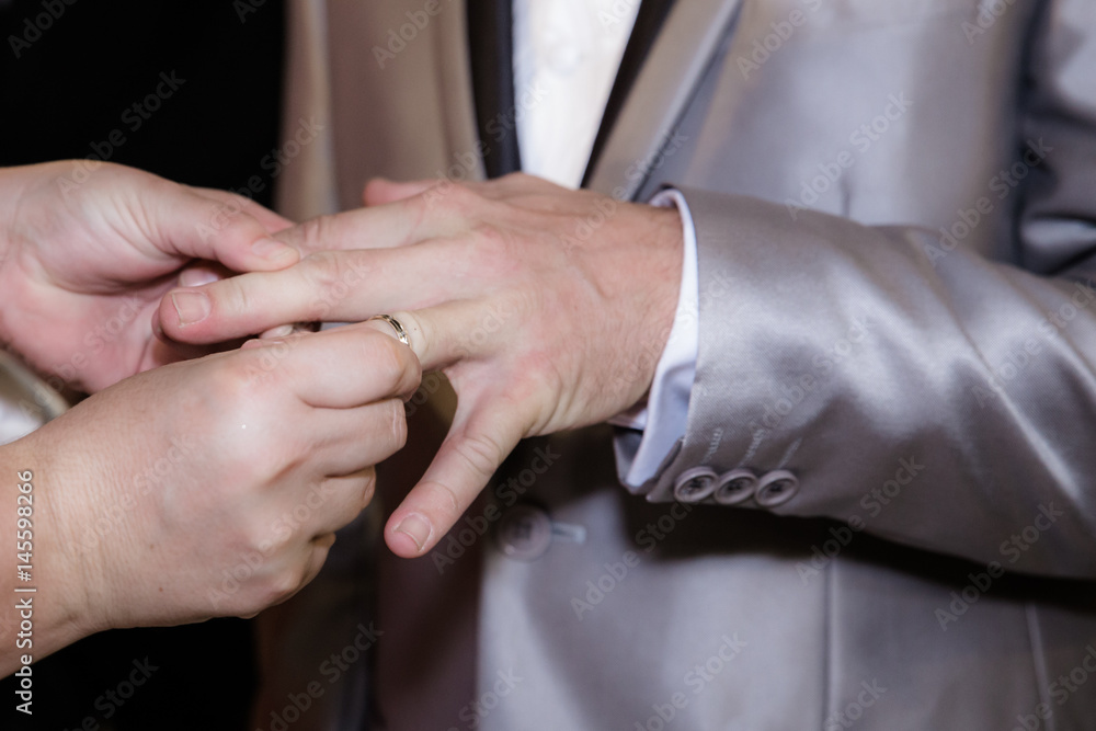 Fototapeta premium Close up hands of bride and groom putting on a wedding rings