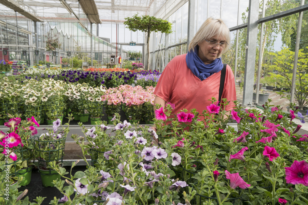 Middle-aged woman chooses flowers at the garden center