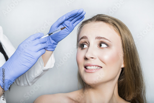 Doctor aesthetician trying to make head beauty injections to female patient