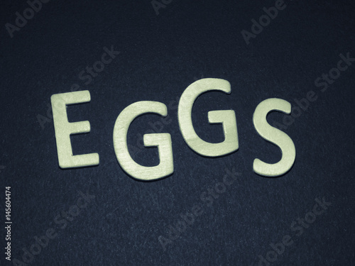 Eggs written with colorful wooden letters on a blue background